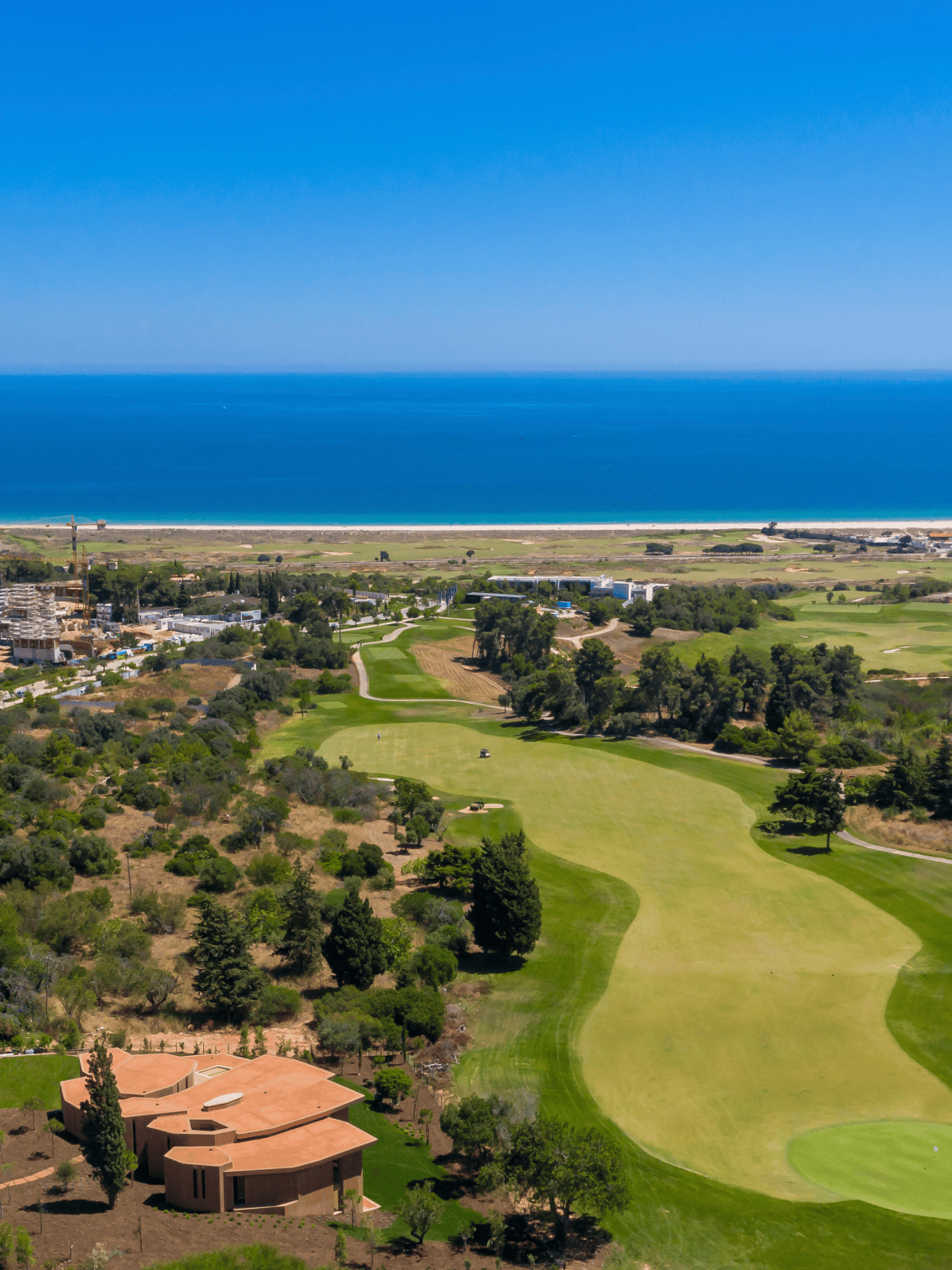 Vista aérea do campo de golfe e do Clubhouse do Palmares, com o mar azul em pano de fundo