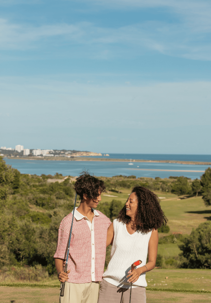 Casal a desfrutar de um momento descontraído no campo de golfe do Palmares, com vista sobre a Ria de Alvor.