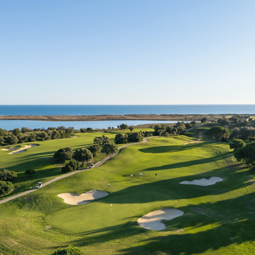 Campo de golfe de Palmares com vista para a ria e o mar, onde um grupo de jogadores desfruta de uma experiência única rodeada de natureza e elegância.