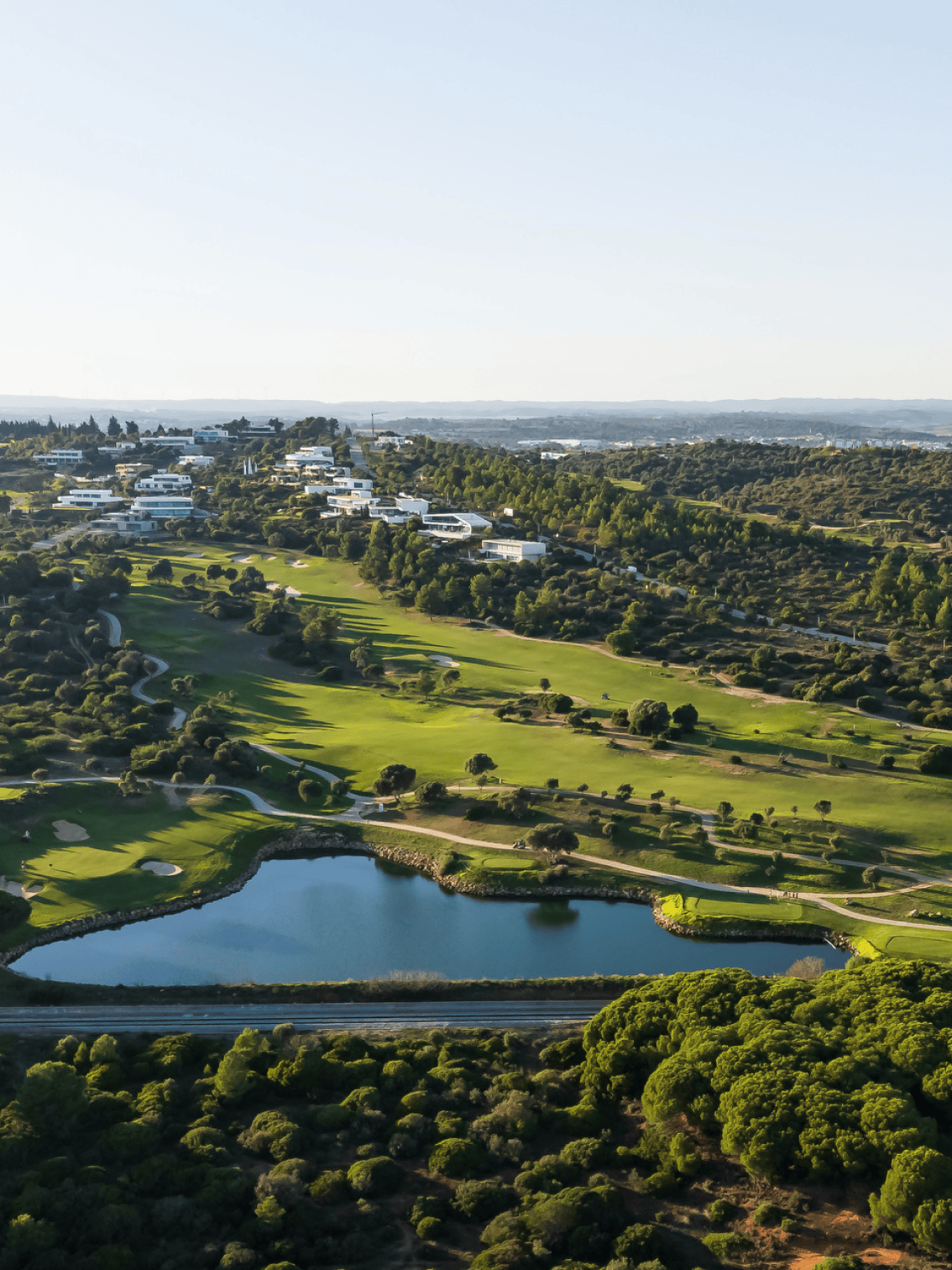 Vista elevada do campo de golfe de Palmares com moradias exclusivas e um lago sereno no centro do resort, rodeado de natureza exuberante.