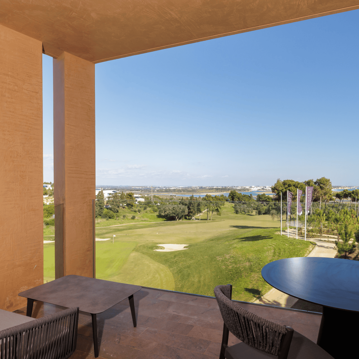 Vista a partir de uma varanda no Palmares Signature Apartments sobre o campo de golfe, com a ria de Lagos e o oceano ao fundo — sofisticação com horizonte aberto.