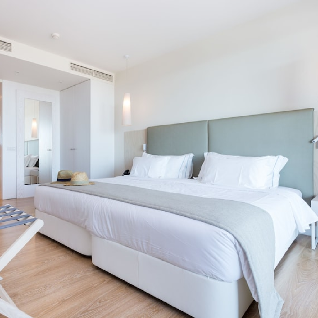 Quarto com cama king-size e decoração minimalista nas suites do Palmares Living, pensado para conforto e descanso.