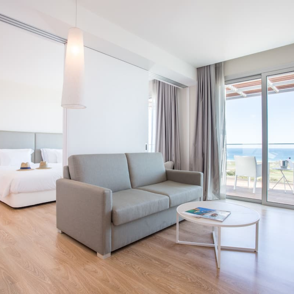 Sala luminosa e moderna nas suites Palmares Living, com acesso direto a varanda e vista mar.