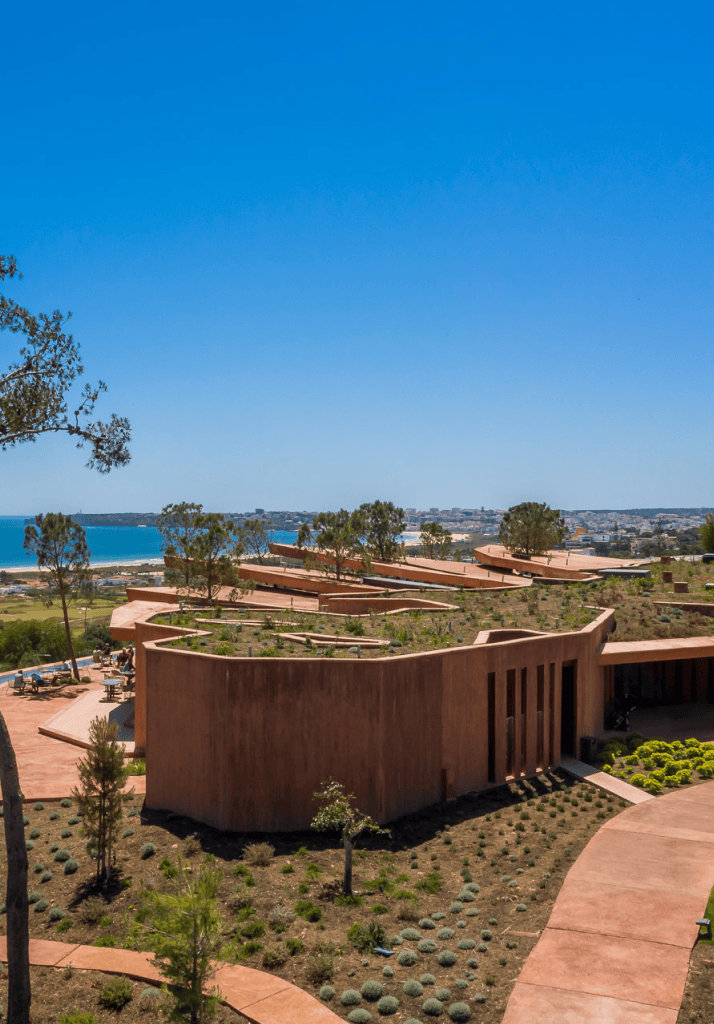 Vista aérea do Signature Clubhouse com rooftop verde e arquitetura integrada na paisagem do resort Palmares.