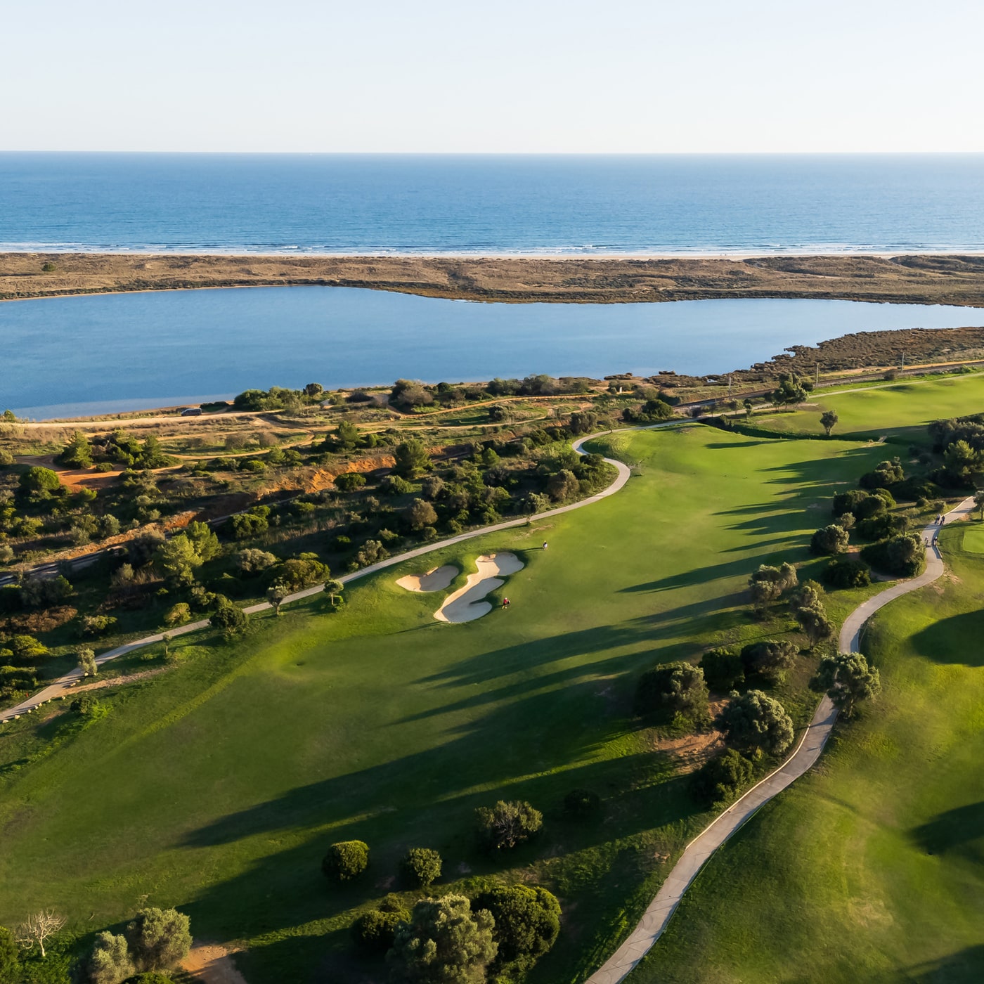 Aerial view of lakeside and parkland fairways at Palmares Golf with Atlantic Ocean backdrop, Lagos, Algarve.